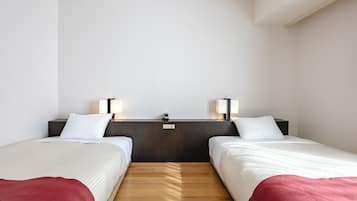 A hotel room with two single beds, a wooden floor, a dark headboard, and bedside lamps.