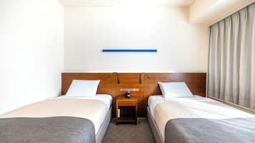 Een hotelkamer met twee bedden, een nachtkastje en een raam met gordijnen.