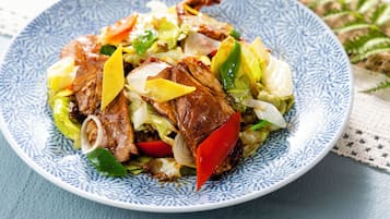 A plate of stir-fried meat with vegetables on a patterned blue and white plate.