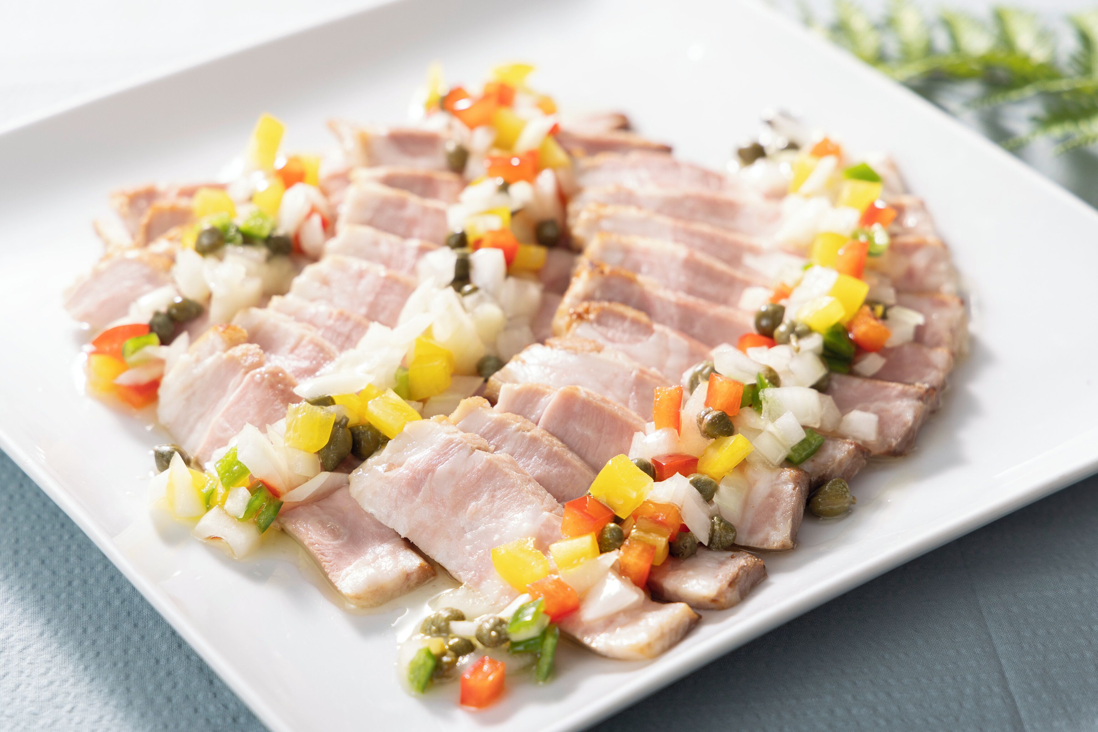 A white plate with sliced meat and diced vegetables.