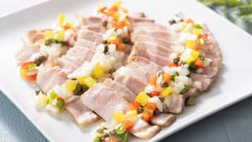 A white plate with sliced meat and diced vegetables.