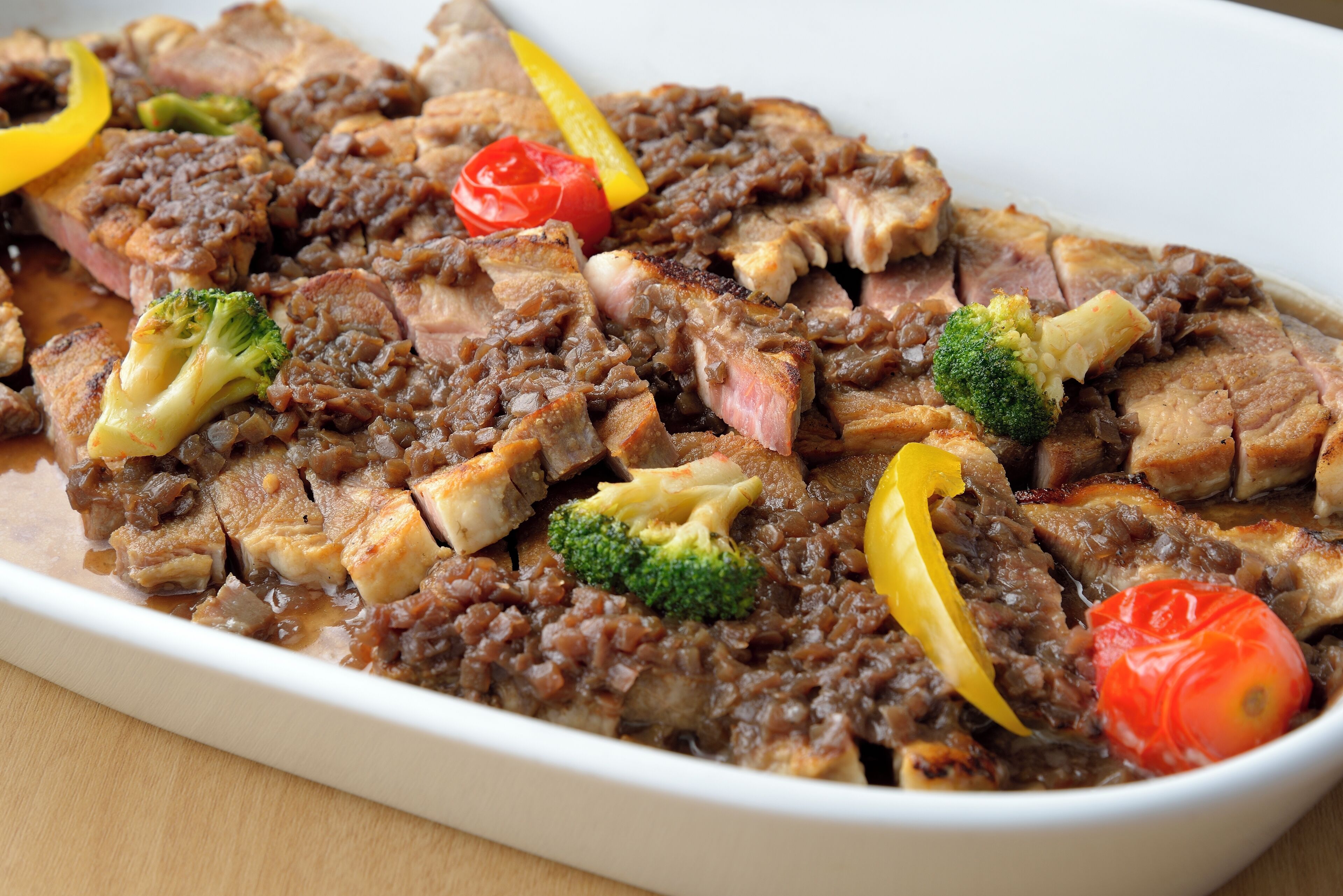 A dish with meat, vegetables, and sauce.