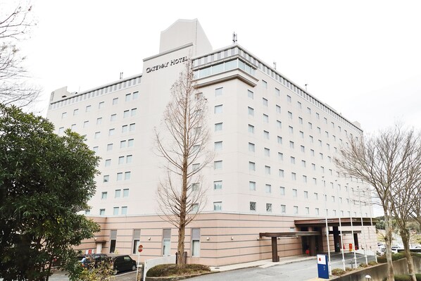 Un hotel de varios pisos con fachada plana, numerosas ventanas y una entrada destacada.