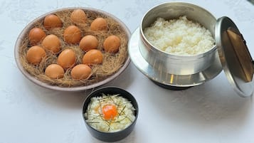 A table with a bowl of rice, a small bowl with an egg, and a bowl of eggs in a nest.