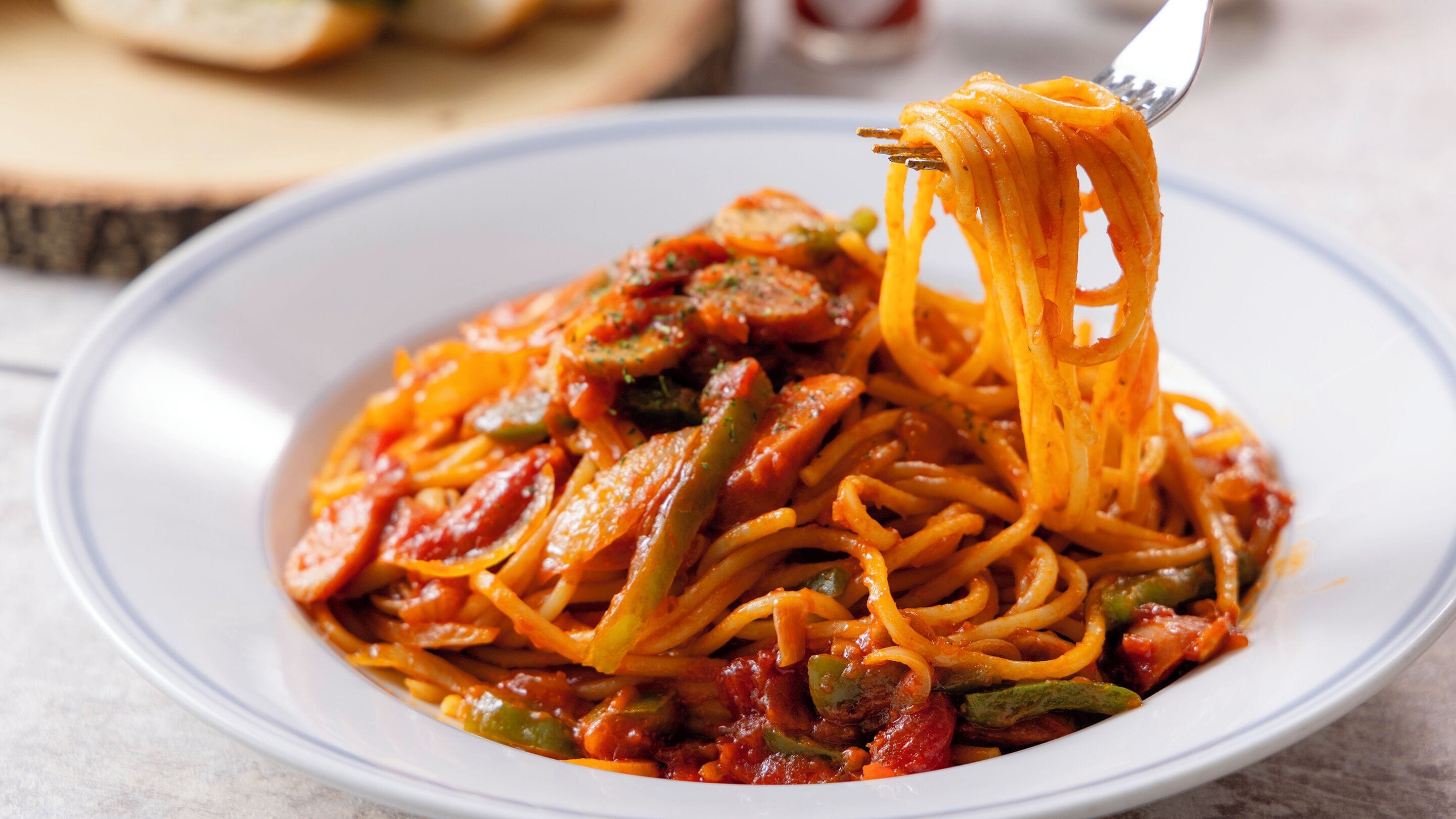 Un plato de espagueti con verduras y salsa.