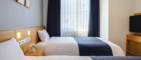 A hotel room with two beds, a TV, a nightstand with a vase of flowers, and a window with curtains.