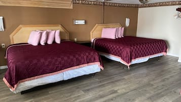 A hotel room with two beds, wooden headboards, and a wooden floor.
