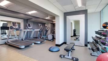 Un gimnasio con cintas de correr, elípticas, remo, pesas libres y pelotas de ejercicio.