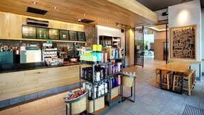 A modern coffee shop interior with a wooden counter, seating area, and various coffee-related products on display.