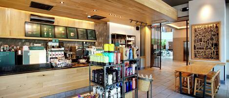 L’intérieur d’un café moderne présente un comptoir en bois, un espace salon et divers produits liés au café, mis en évidence.