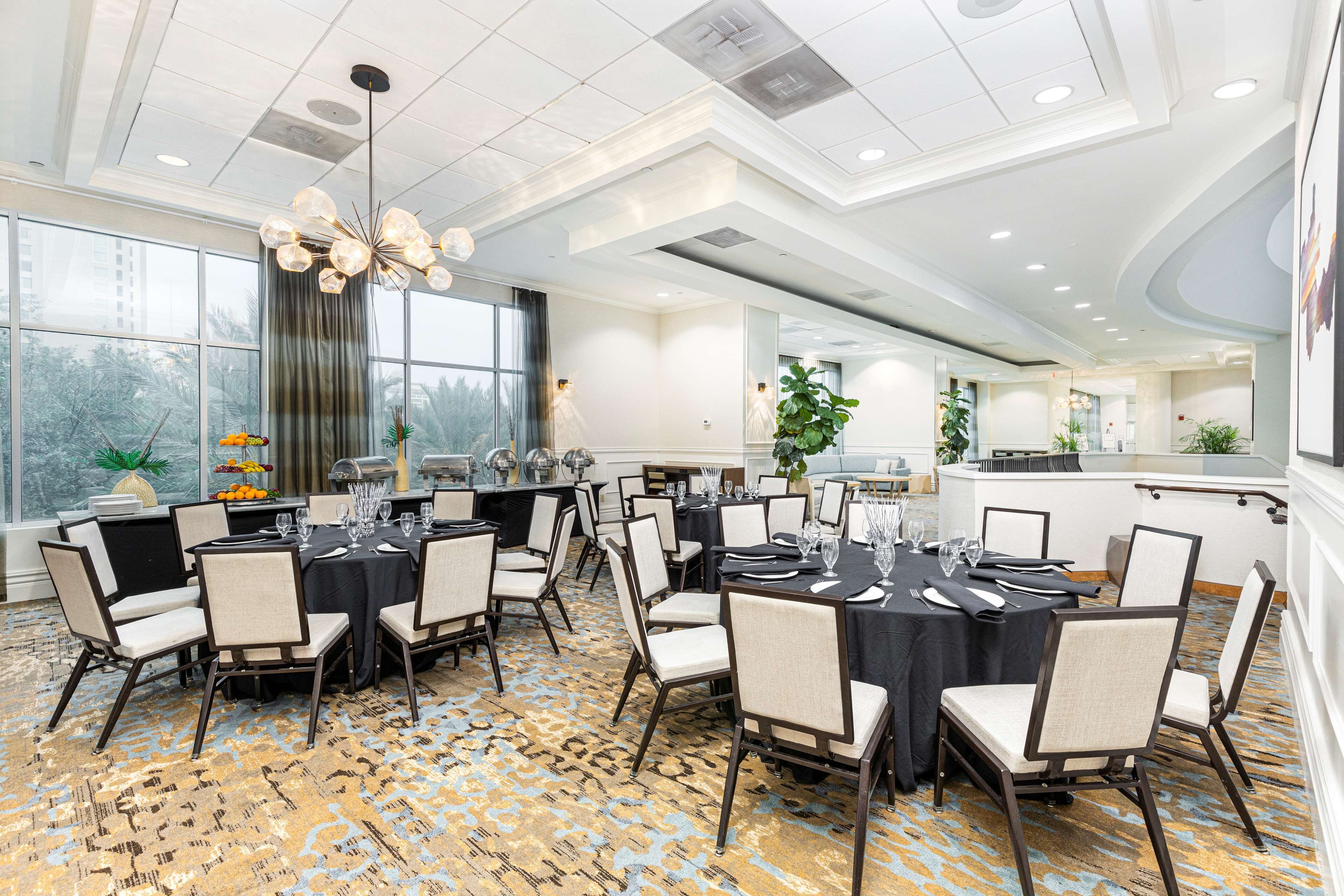A conference room with round tables, chairs, and a chandelier.