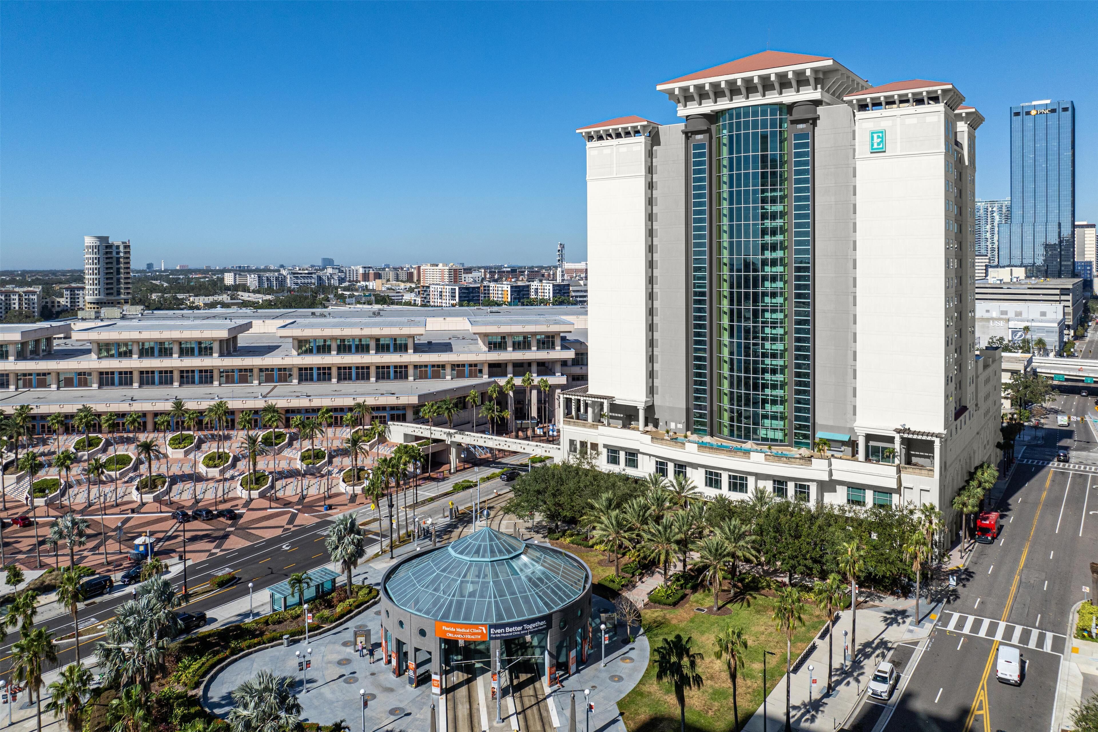 Un hotel moderno con una fachada de vidrio destacada, un jardín en la azotea y un atrium circular.