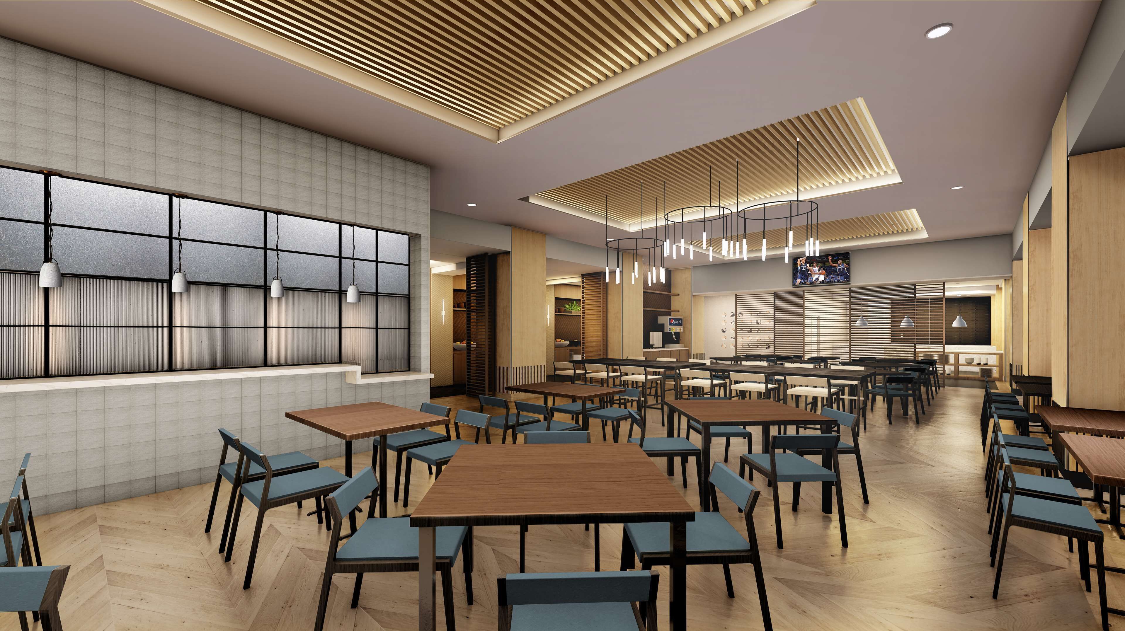 Un restaurant spacieux, doté de nombreuses tables et chaises, d’une grande fenêtre avec des stores et d’un téléviseur fixé au mur.