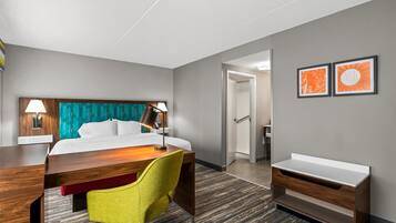 A hotel room with a bed, desk, chair, and a small bathroom area.