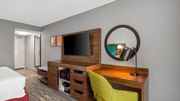 Ein Hotelzimmer mit Bett, Schreibtisch mit Stuhl, Fernseher, Spiegel und einer Mikrowelle.