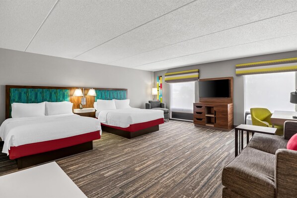 A hotel room with two beds, a TV, a desk, and a chair.