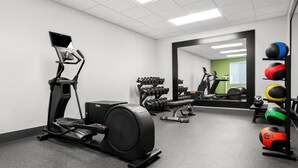 A gym with exercise equipment, including a treadmill, weights, and a mirror reflecting the space. - Spark by Hilton Grand Island (Grand Island)
