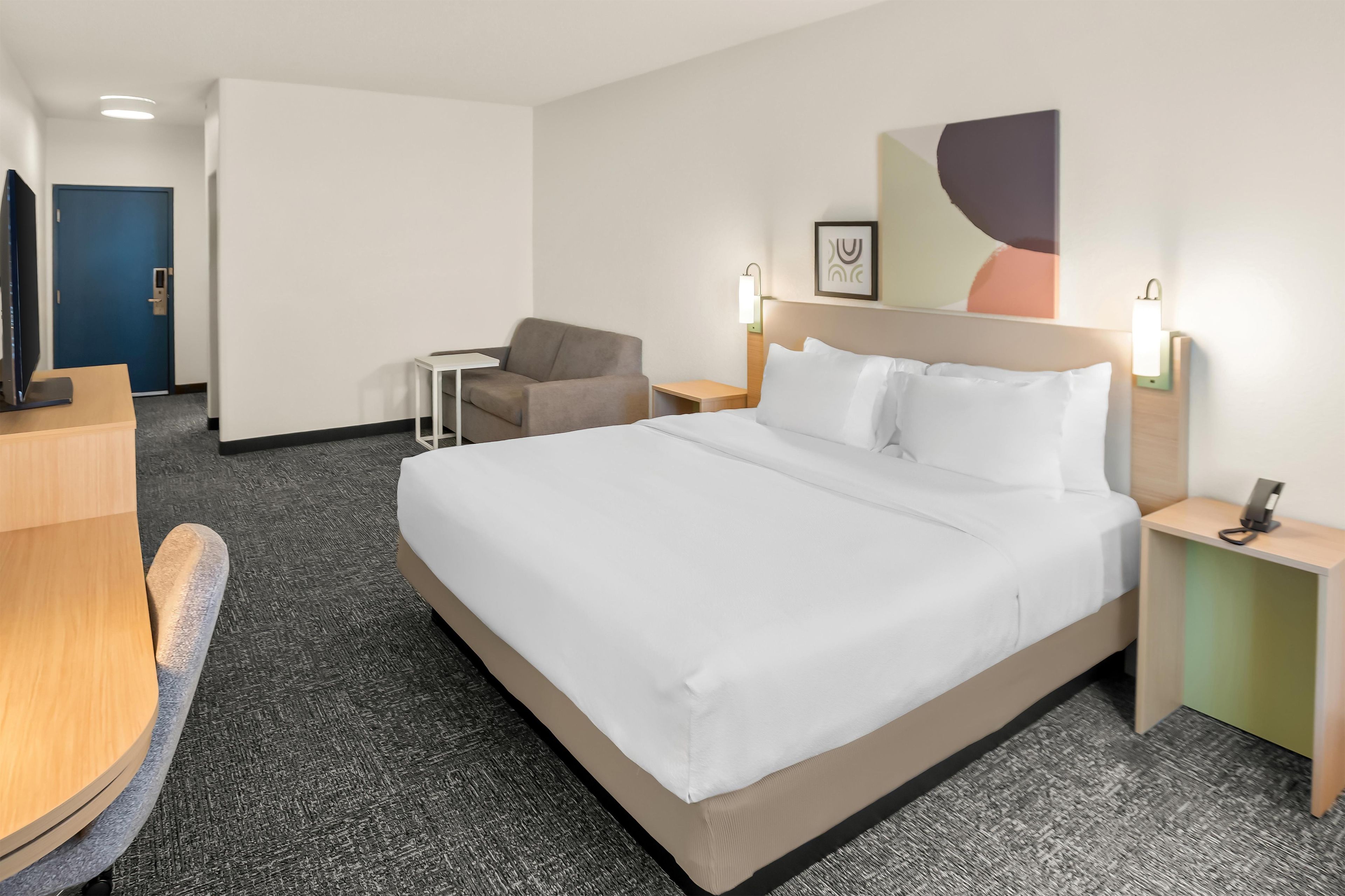 Ein Hotelzimmer mit einem großen Bett, einem Schreibtisch, einem Stuhl und einem kleinen Tisch.
