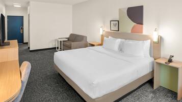 Une chambre d’hôtel avec un grand lit, un bureau, une chaise et une petite table.