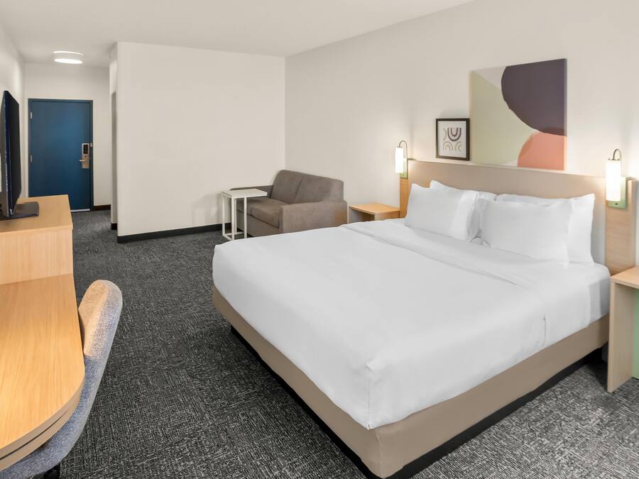Ein Hotelzimmer mit einem großen Bett, einem Schreibtisch, einem Stuhl und einem kleinen Tisch.