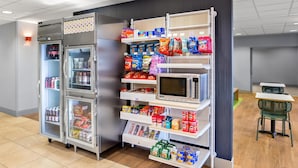A vending machine area with snacks, drinks, and a microwave. - Spark by Hilton Grand Island (Grand Island)