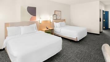 A hotel room with two single beds, a nightstand, a phone, and a wall-mounted light fixture.