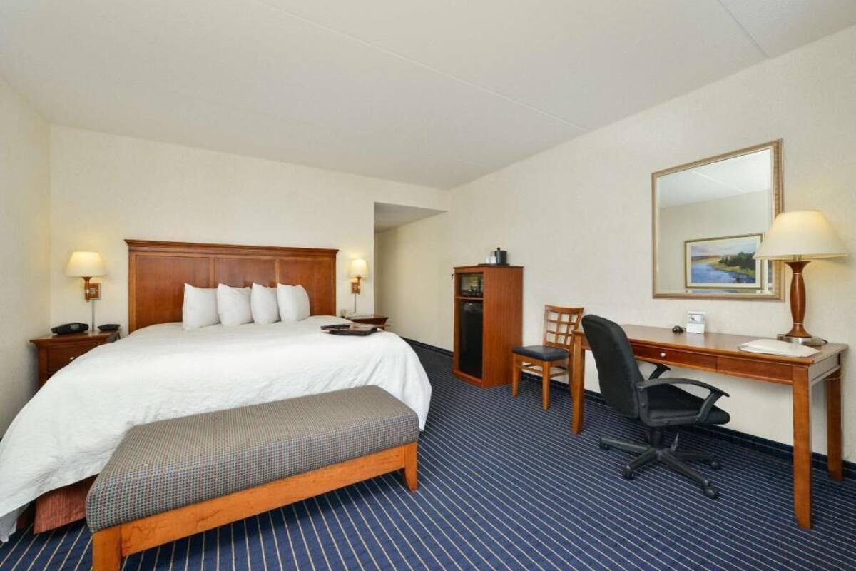 Ein Hotelzimmer mit Bett, Schreibtisch, Stuhl und einem kleinen Schrank.