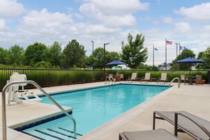 A swimming pool with a lifeguard stand, lounge chairs, and umbrellas.