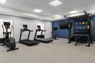 Un gimnasio con cintas de correr, una bicicleta estática y una zona de levantamiento de pesas.