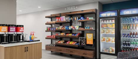 A food service area with a coffee station, snack shelves, and beverage dispensers.