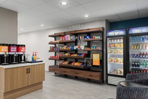 Un espacio de comida con una estación de café, estantes de aperitivos y dispensadores de bebidas.