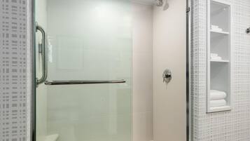 Un bagno moderno con box doccia in vetro, porta in vetro e parete rivestita di piastrelle bianche.