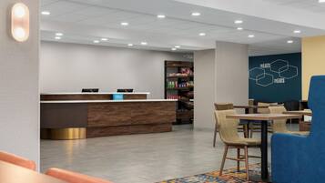 Una hall d'albergo con una reception, una zona salotto e un muro con un motivo geometrico.