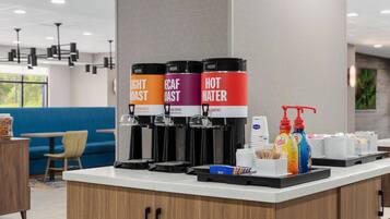 A coffee station with three dispensers labeled 'Light Roast,' 'Decaf Roast,' and 'Hot Water.'