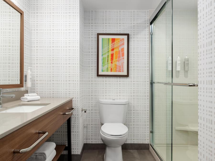 A bathroom with a wooden vanity, a white toilet, and a glass shower enclosure.