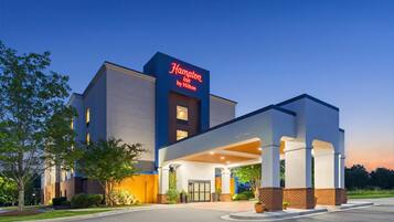 Un hotel Hampton Inn by Hilton con una facciata moderna, un ingresso coperto e un cartello accogliente.
