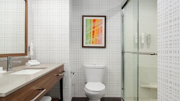 A bathroom with a wooden vanity, a white toilet, and a glass shower enclosure.