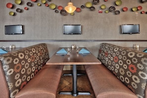A restaurant interior with booths, a table, and wall-mounted televisions. - Holiday Inn & Suites Albuquerque-North I-25 by IHG (Albuquerque)