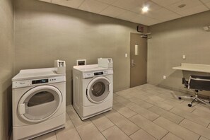 A laundry room with two front-loading washers and dryers, a small sink, and a door marked 'EXIT'.