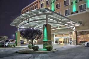 A hotel entrance with a covered walkway, a parking area, and a building facade with windows. - Holiday Inn & Suites Albuquerque-North I-25 by IHG (Albuquerque)