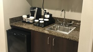 Eine kompakte Küche mit Mikrowelle, Kaffeemaschine und Spüle.