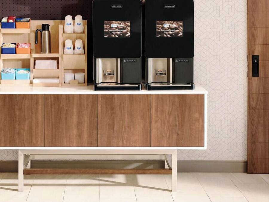 A counter with two coffee machines, a kettle, and storage shelves with various items.