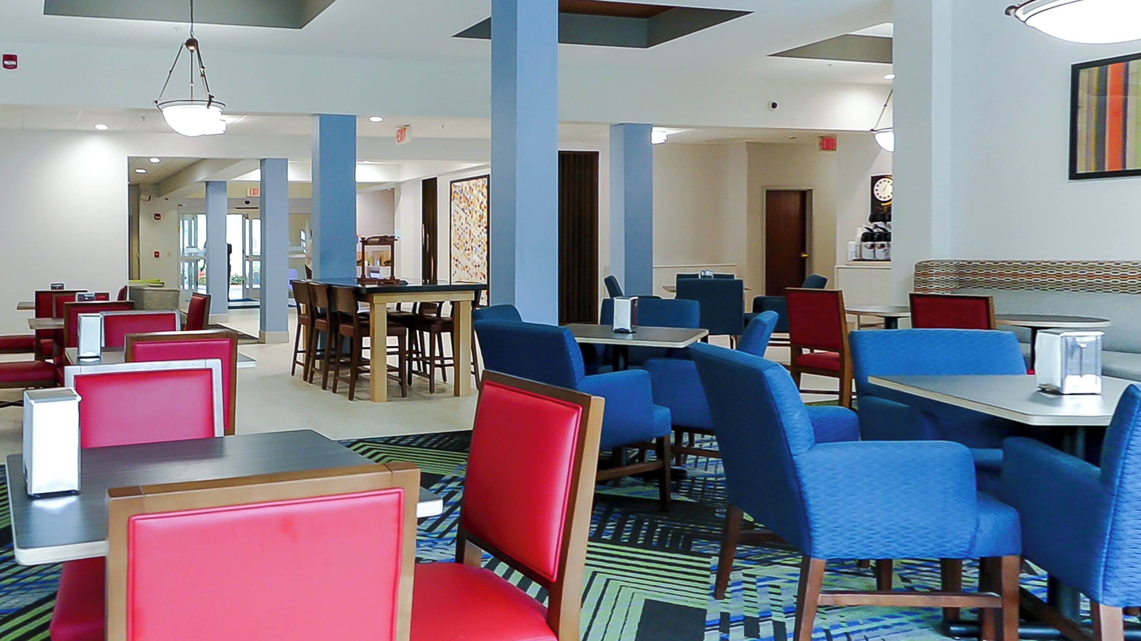 A restaurant with booths and tables, blue and red seating, and a patterned carpet.