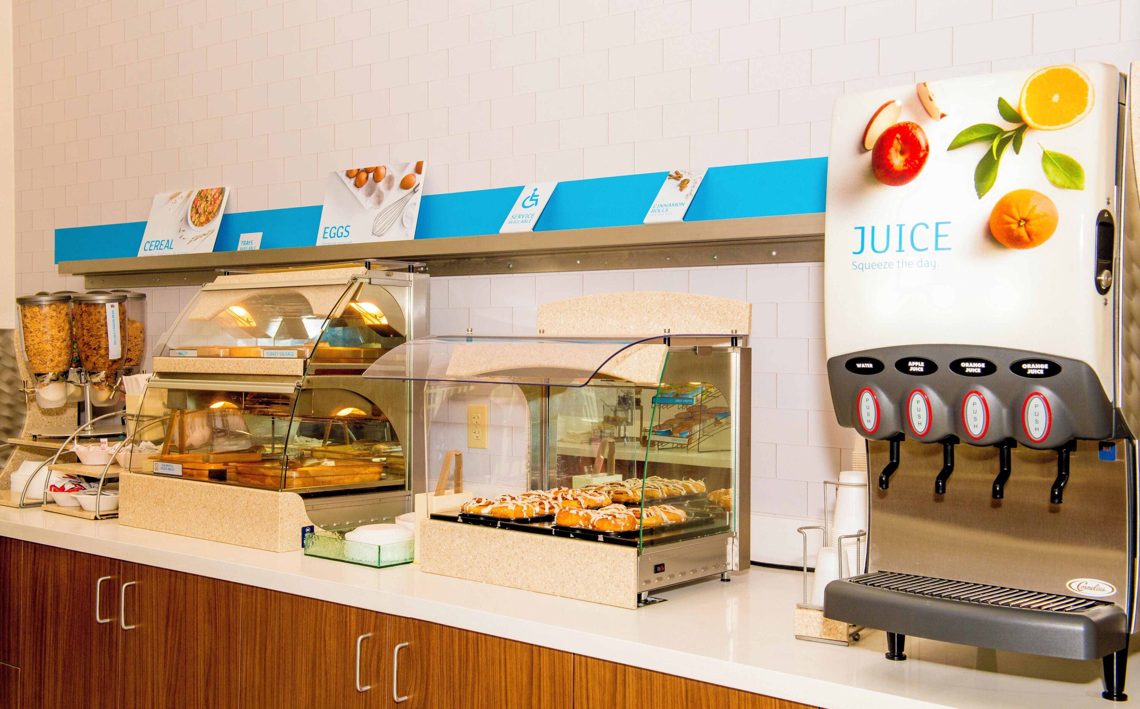 A self-serve breakfast station with various food options and a juice dispenser.