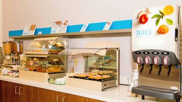 A self-serve breakfast station with various food options and a juice dispenser.