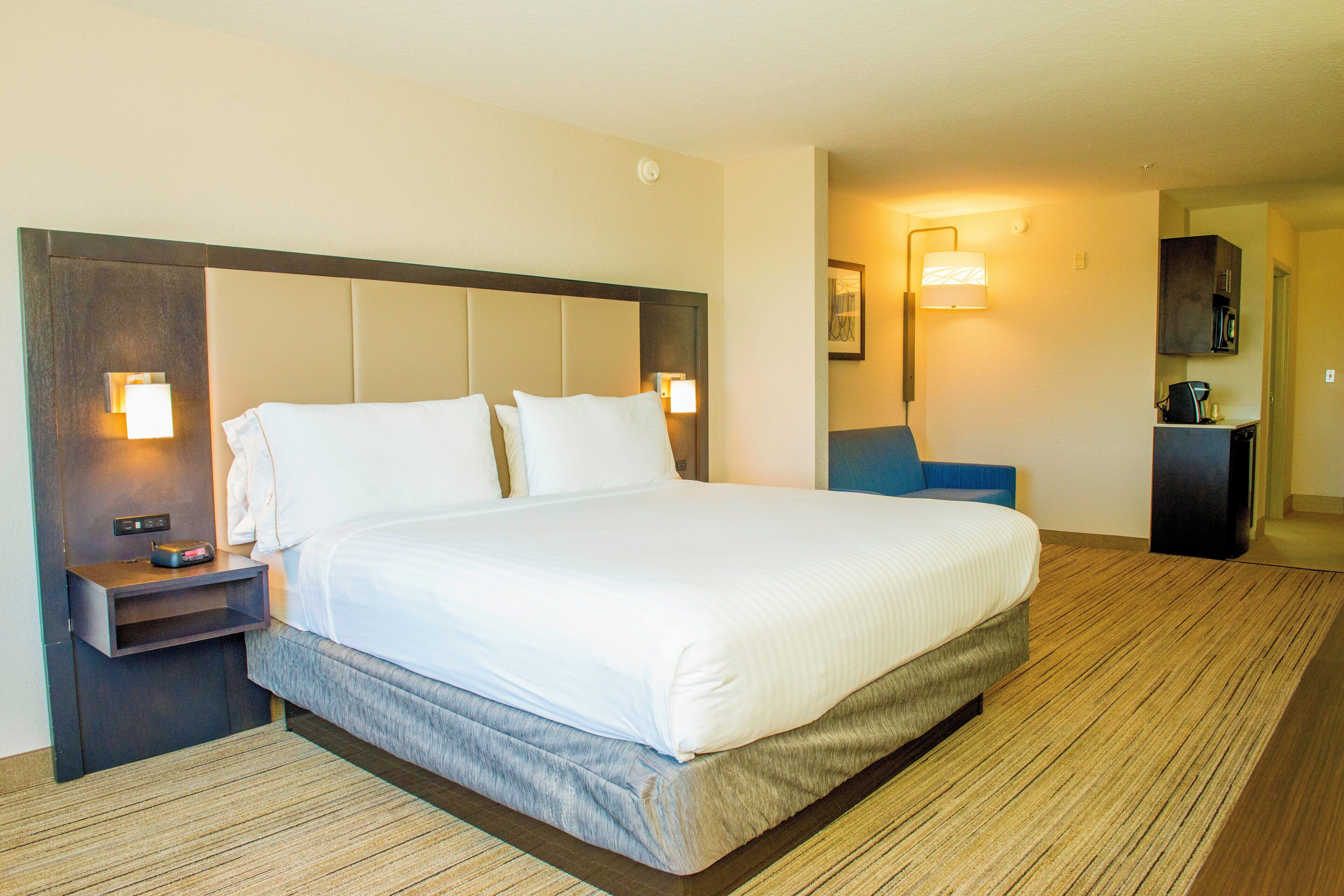 A hotel room with a large bed, bedside tables, a desk, and a chair.