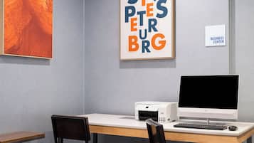 Un espacio de trabajo con un ordenador de escritorio, una impresora y dos sillas.