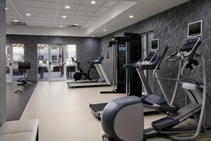 Une salle de sport équipée de tapis de course, de vélos elliptiques et de matériel de musculation.