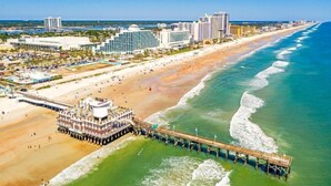 A coastal cityscape with a beach, a pier, and high-rise hotels. - Homewood Suites by Hilton Daytona Beach Speedway-Airport (Daytona Beach)
