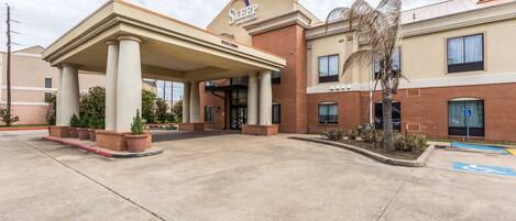 A Sleep Inn with a covered entrance, brick facade, and a parking area with a handicapped parking sign.